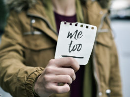 Frau hält Zettel mit Aufschrift "me too"