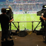 Zwei Kameras filmen ein Fußballspiel in einem großen Fußballstadion