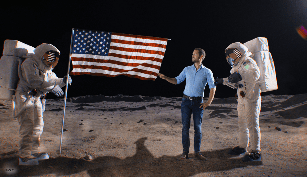 Terra X Moderator Mirko Drotschmann per digitalem Effekt auf dem Mond, die Flagge der USA haltend.