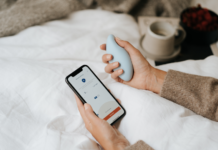 Atemtrainer in der einen, Smartphone in der anderen Hand. Das Gerät soll Schlafstörungen lindern