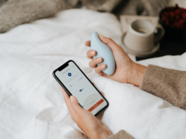 Atemtrainer in der einen, Smartphone in der anderen Hand. Das Gerät soll Schlafstörungen lindern