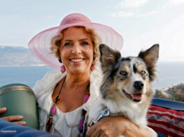 Michaela May mit Hund, Hut und einer Urne im Cabrio