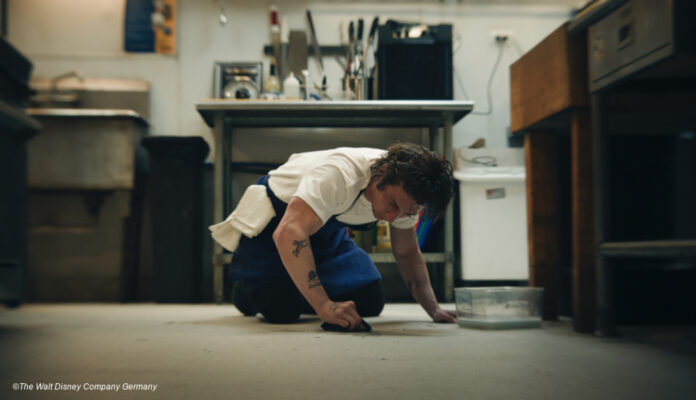 Junger Mann putzt den Küchenboden