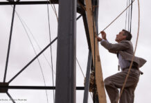 Szene aus "Oppenheimer": Cilian Murphy klettert an einem Turm hinauf