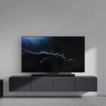 LG Soundbar mit Subwoofer vor Fernseher, auf dessen Display ein Blitz zu sehen ist. Vorschau auf die LG Neuheiten bei der CES 2023