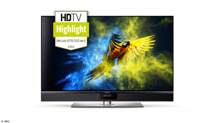 Metz Lunis 42 OLED TV mit Test Siegel vom HDTV Magazin. Ein farbenfroher Papagei ist auf dem sonst schwarzen Bildschirm zu sehen.