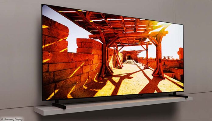Un televisor Samsung QD OLED de 77 pulgadas frente a la pared de una sala de estar beige.  La pantalla del televisor muestra una escena de película brillante desde un área al aire libre con sombras proyectadas.