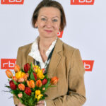 Martina Zöllner mit Blumenstrauß vor RBB-Wand
