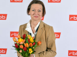 Martina Zöllner mit Blumenstrauß vor RBB-Wand