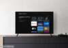Ein Roku TV von Sharp in einem Beispielbild vor einer weißen Wand auf einem Sideboard