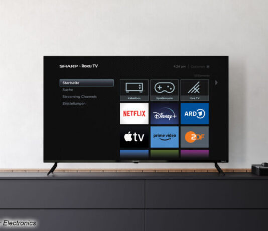 Ein Roku TV von Sharp in einem Beispielbild vor einer weißen Wand auf einem Sideboard