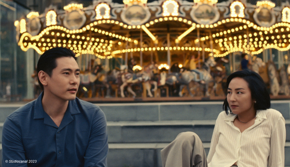 Nora und Hae Sung vor einem Karussell in "Past Lives"