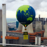 Ein Heißluftballon von Greenpeace vor einem Kohlekraftwerk