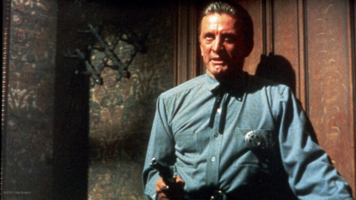 Sheriff Matt Morgan (Kirk Douglas) steht in einer Tür und hält eine Pistole in der Hand.