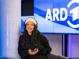 Frau mit Kopfhörern vor ARD-Logo