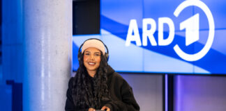 Frau mit Kopfhörern vor ARD-Logo
