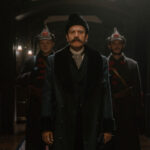 Szene aus "Ein Gentleman in Moskau": Der Graf steht im Hotel, dahinter zwei Soldaten. (Paramount+)