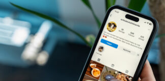 Hand mit Smartphone, auf dessem Bildschirm die für die Doku "Jung, viral, rechtsradikal?" erstellte Fake-Koch-Seite zu sehen ist