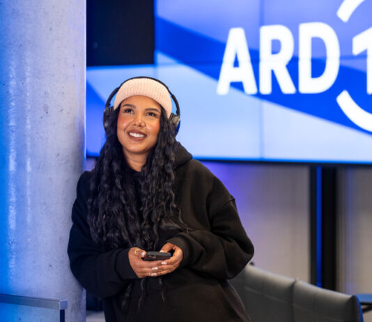 Frau mit Kopfhörern unter dem ARD Logo