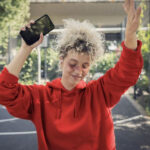 Eine Frau mit Smartphone tanzt.