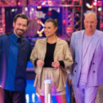 Jan Köppen, Laura Wontorra und Frank (Buschi) Buschmann stehen nebeneinander im Ninja-Warrior-Studio und lachen in die Kamera