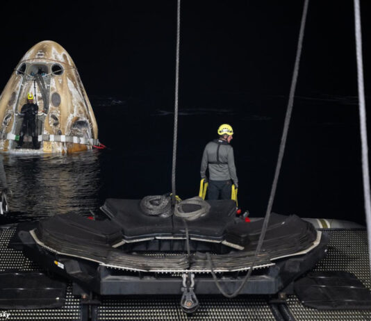 Drei Arbeitende bereiten den Abtransport des schwimmenden "Crew Drageon Endeavour" vor, das im Hintergrund im Meer schwimmt.