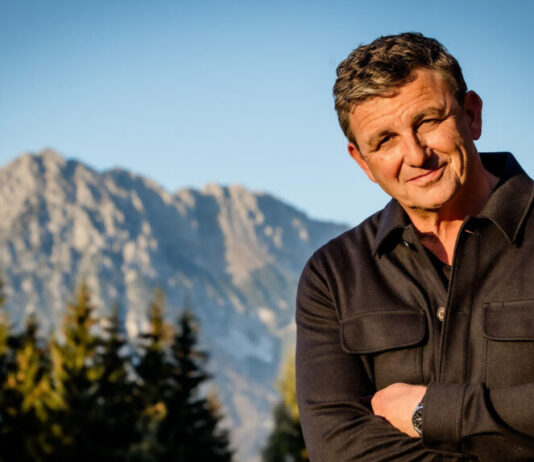 Schauspieler Hans Sigl steht vor einem Bergpanorama