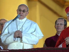 Ein Foto des Papstes Franziskus, der auf dem Balkon vor dem Petersplatz in ein Mikrofon spricht.