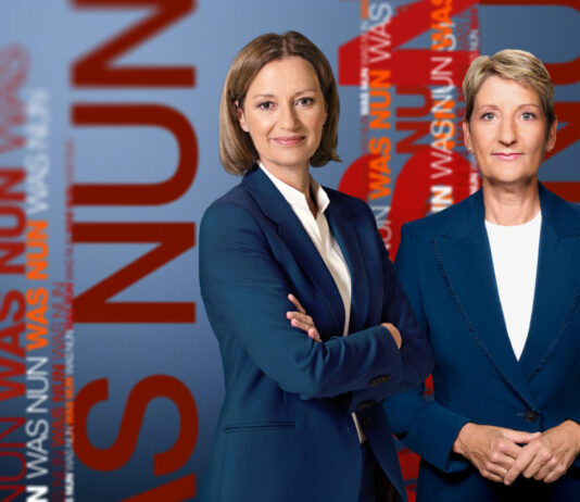 Bettina Schausten und Anne Gellinek schauen in die Kamera, im Hintergrund und daneben steht der Schriftzug "WAS NUN".