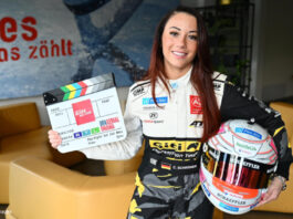 Carrie Schreiner mit Rennfahrerhelm und Filmklappe