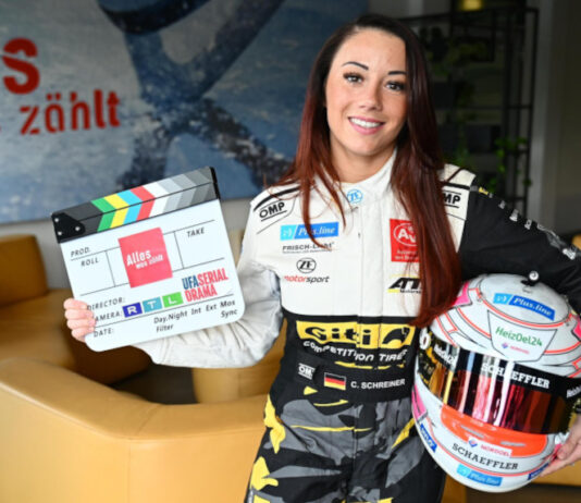 Carrie Schreiner mit Rennfahrerhelm und Filmklappe
