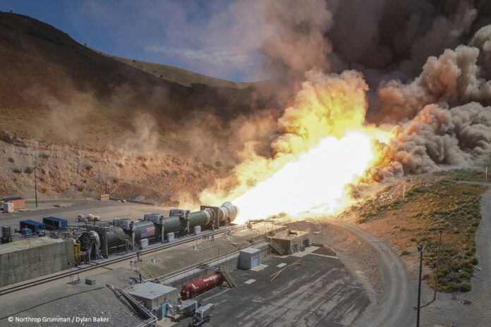df_BOLE_test_fire_SLS Ein horizontal am Boden montiertes Raketentriebwerk wird getestet. Aus der Rakete tritt ein in Richtung eines Hügels gerichteter, großer Feuerball aus.