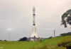 Eine weiße Rakete steht auf ihrer Startposition, im Hintergrund ein diesiger Himmel.