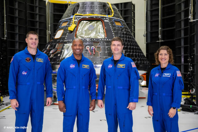 df_artemis-2_crew Die voraussichtliche Crew von "Artemis 2" steht in blauen Overalls vor dem Orion-Raumschiff in einer Fertigungshalle. Von links nach recht: Jeremy Hansen, Victor Glover, Reid Wiseman, Christina Hammock Koch.