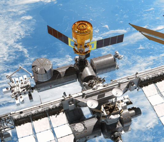 Ein Renderbild zeigt die Internationalen Raumstation mit einem angedockten "HTV-X"- Raumfrachter von "oben". Im Hintergrund sieht man das Blau der Erde und ein paar Wolken.